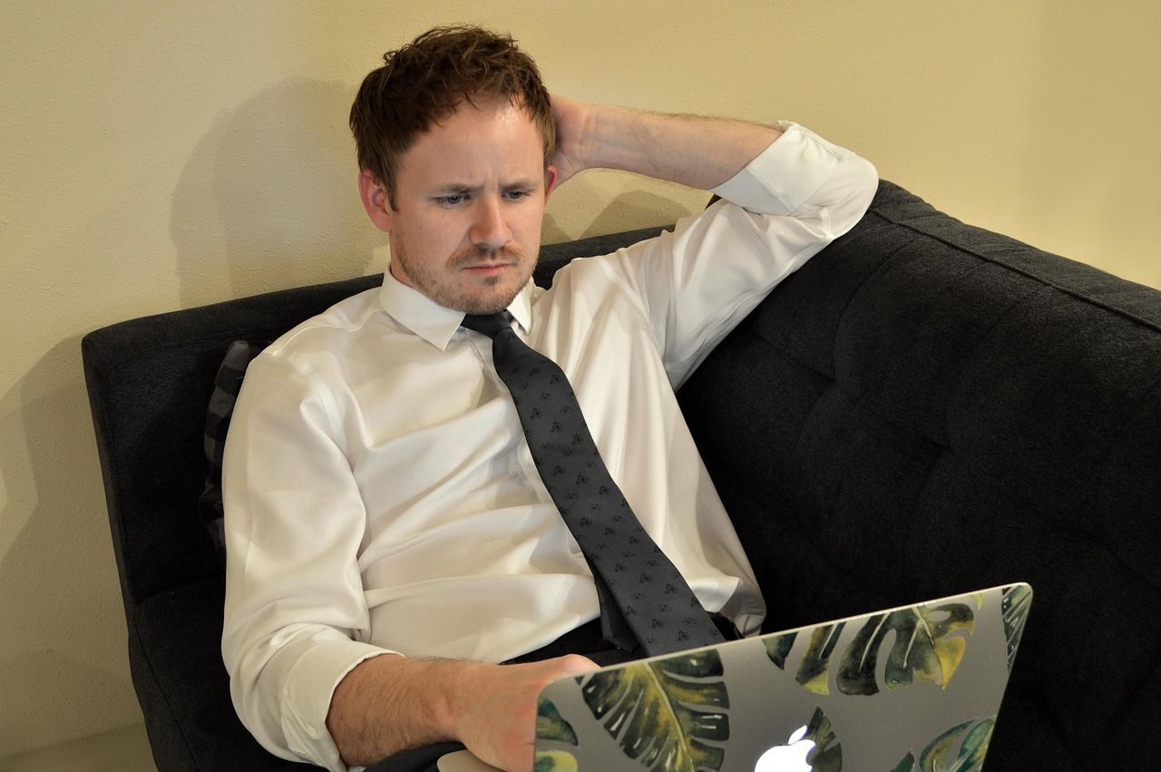 Mann arbeitet mit Laptop auf einem Sofa